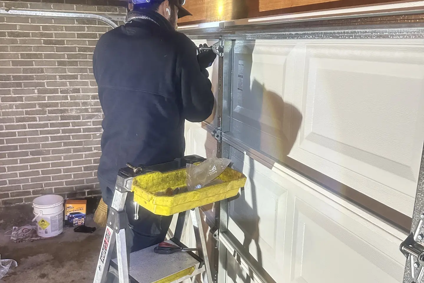 Technician inspecting garage door track and hardware