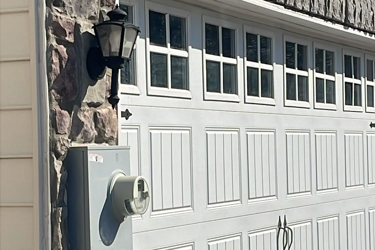 Completed white garage door installed on a stone-front home
