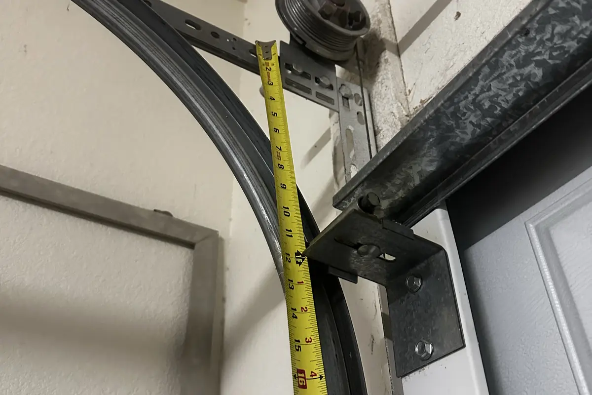 Garage door track and cable hardware being measured